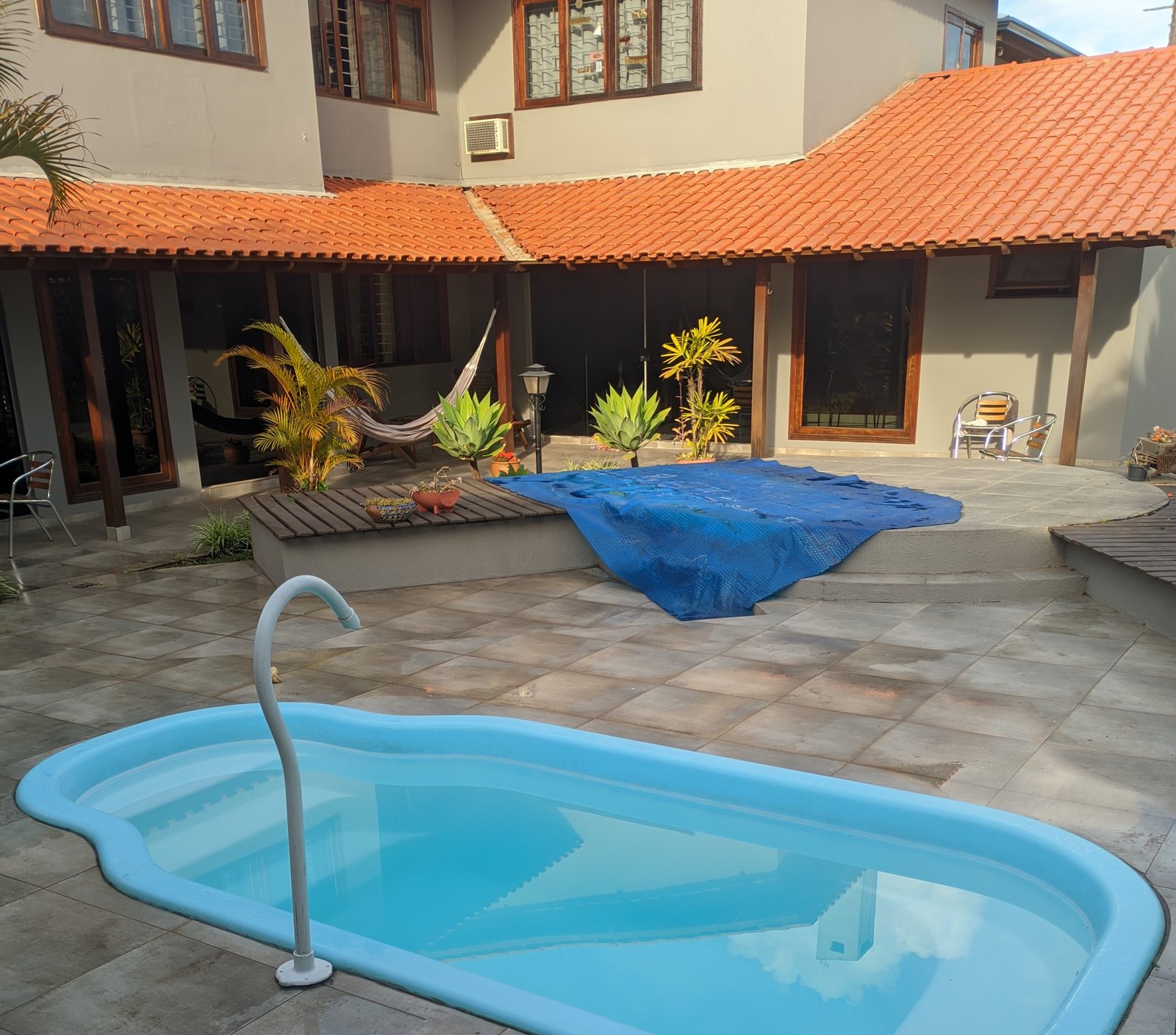 Piscina de fibra com água clara em frente à casa